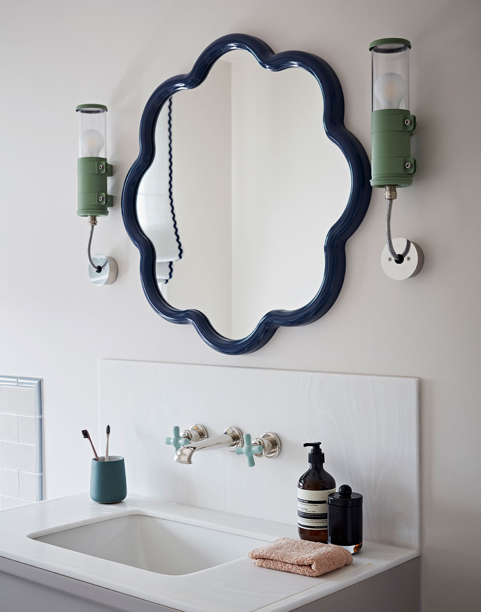 Flower-shaped bathroom mirror and unusual lights above a bathroom sink