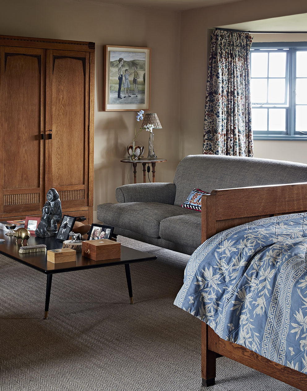 Cosy bedroom of a luxury rural home with vintage wooden wardrobes and stunning upholstered sofa in muted tones.