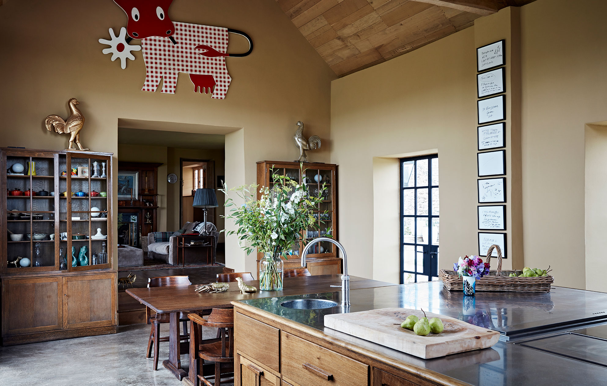 Bespoke dark wood kitchen in luxury farmhouse with soft ochre limewash walls, wooden furniture and quirky modern art.