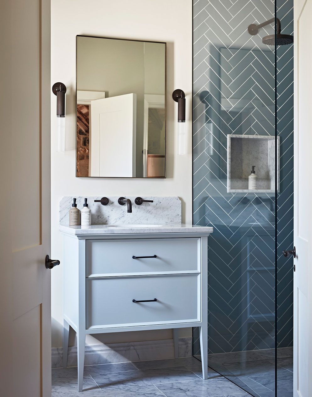 Guest bathroom design in luxury country house with marble splashback and herringbone tiles.