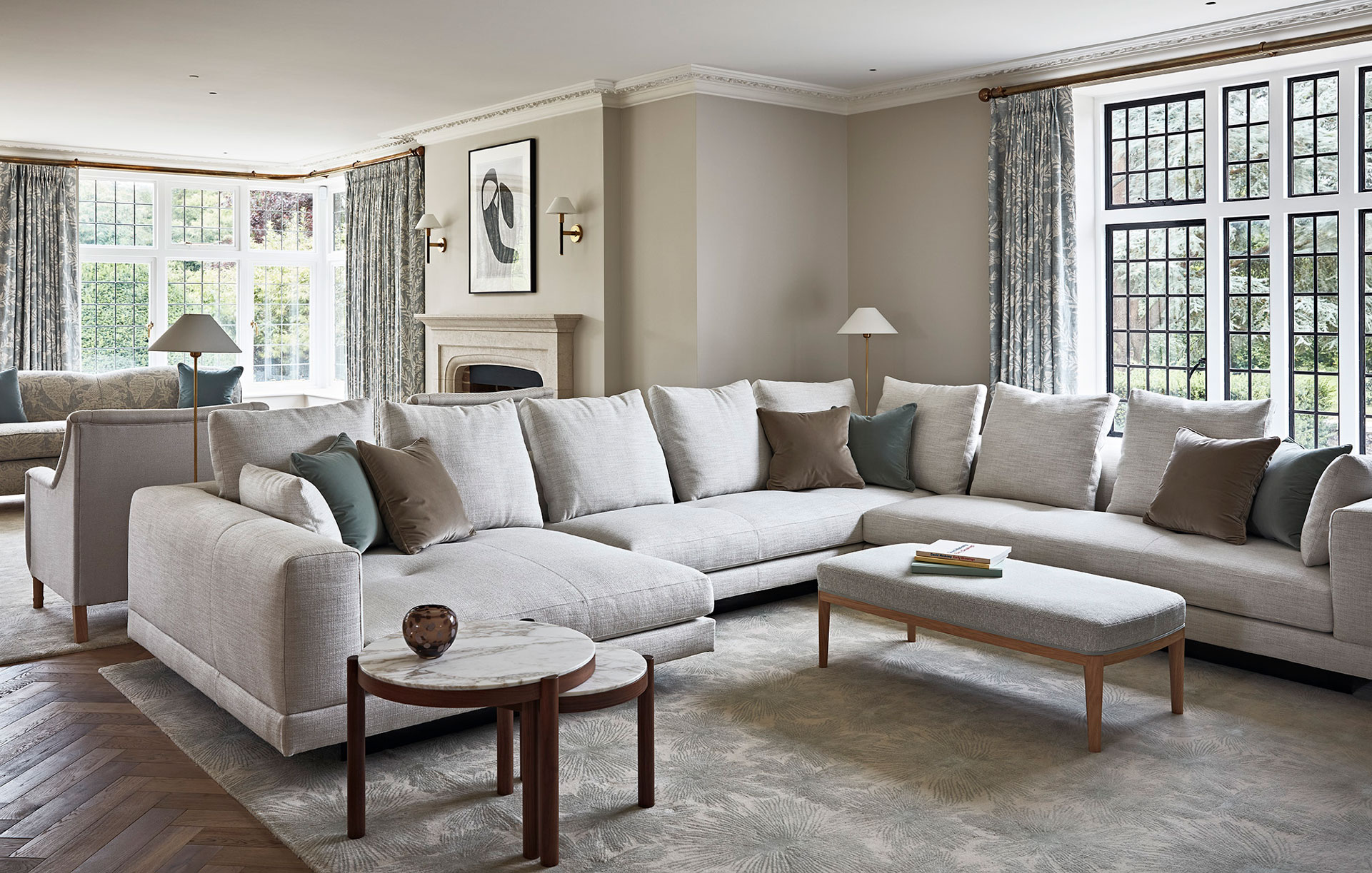 Soft muted drawing room with large sofas and grey rugs on a parquet floor.