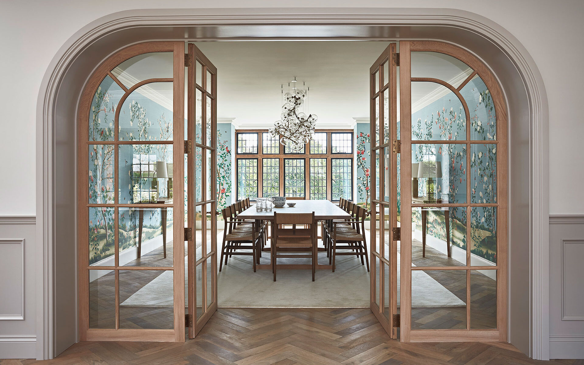 Stunning luxury dining room in a manor house with colourful walls, wooden parquet floor and glass chandelier.